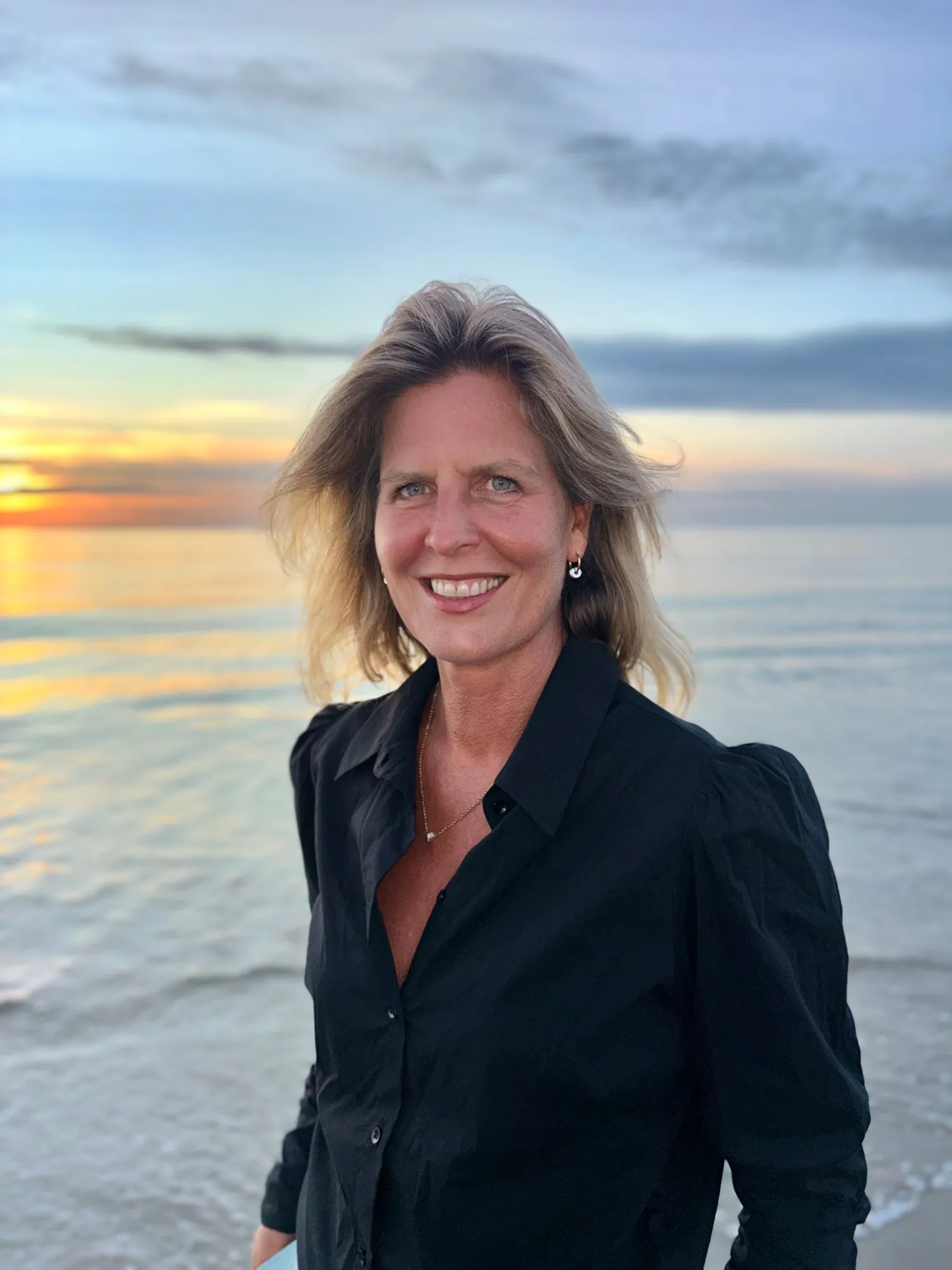 Suzanne de Moor aan zee bij zonsondergang