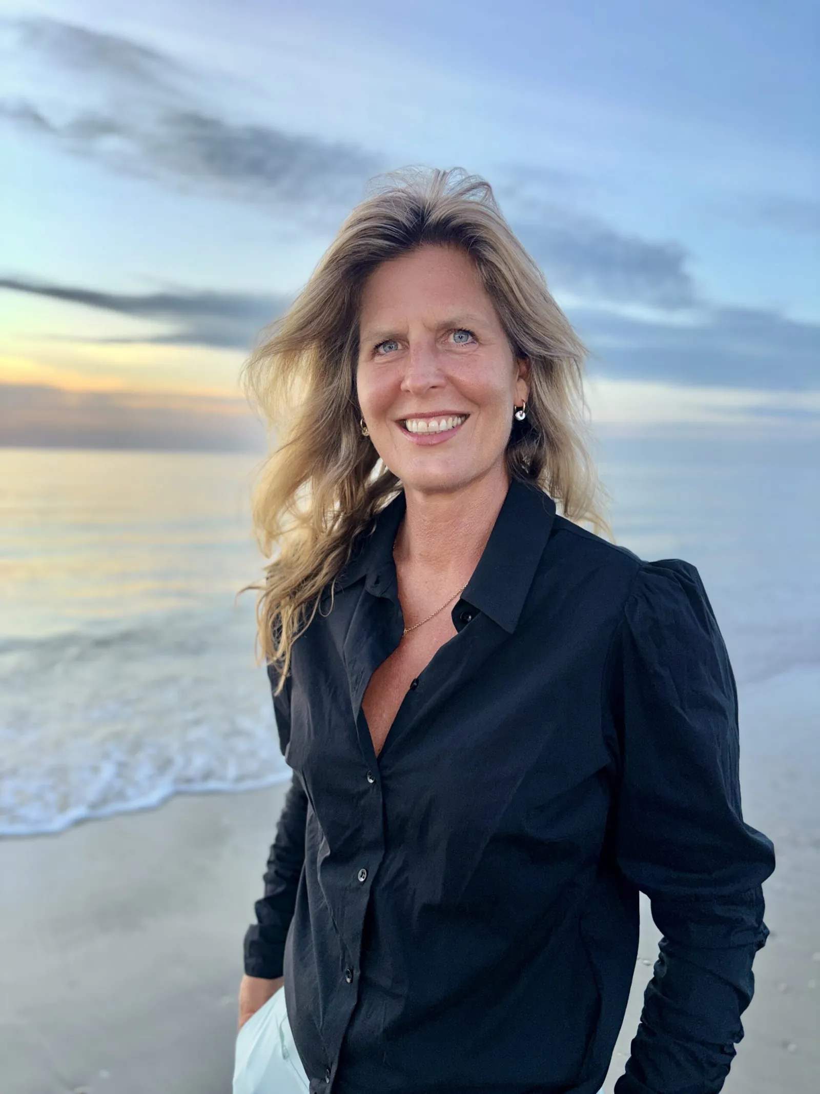 Suzanne de Moor aan zee bij zonsondergang